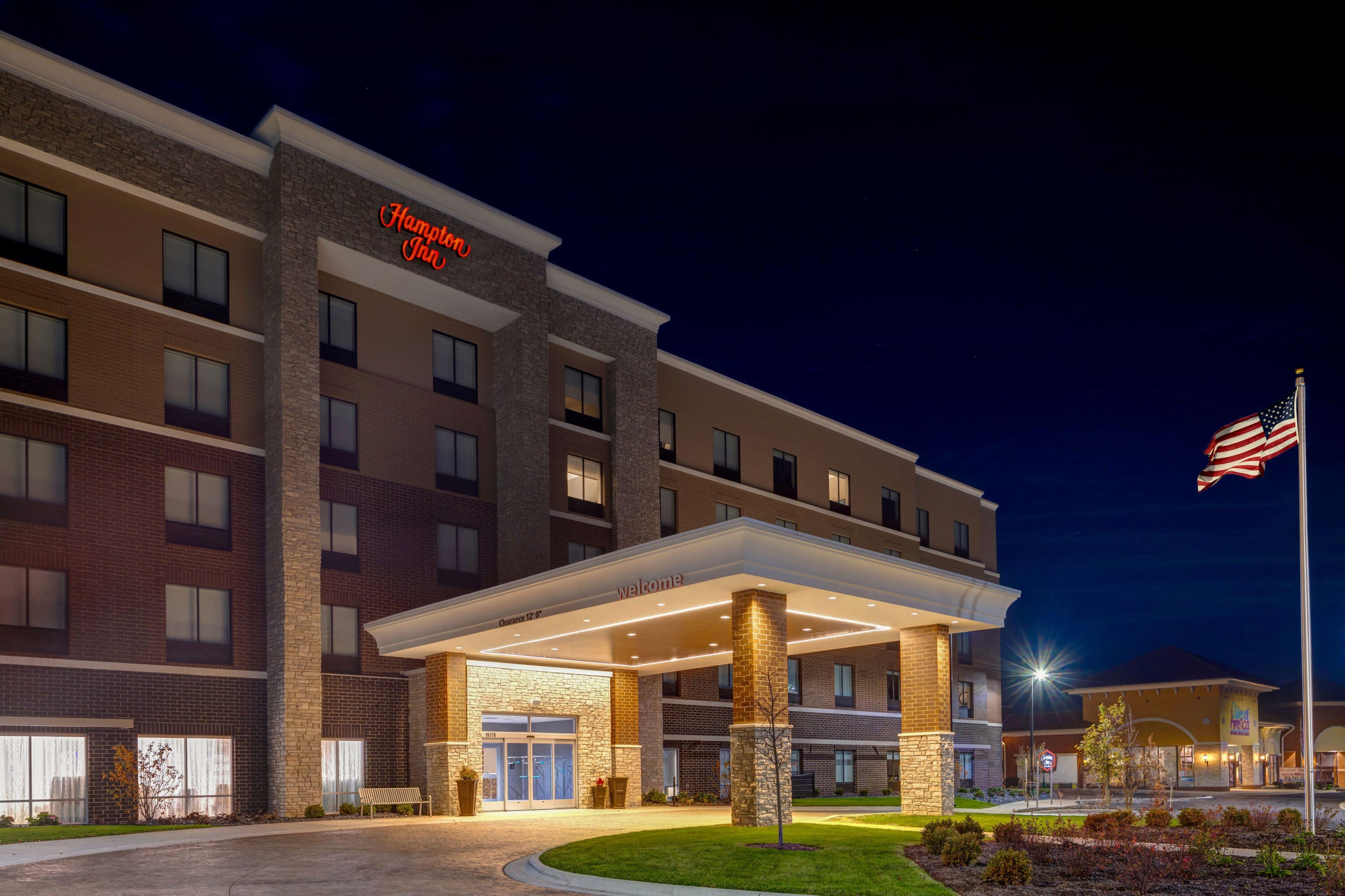 A hotel with a stone facade, a clear entrance, and an American flag.