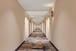 A long, narrow hotel corridor with a patterned carpet and evenly spaced doors on both sides. - Hampton Inn Chicago Orland Park (Orland Park)
