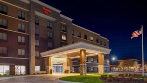 Un hotel con fachada de ladrillo, un cartel de 'Welcome' y una bandera estadounidense.