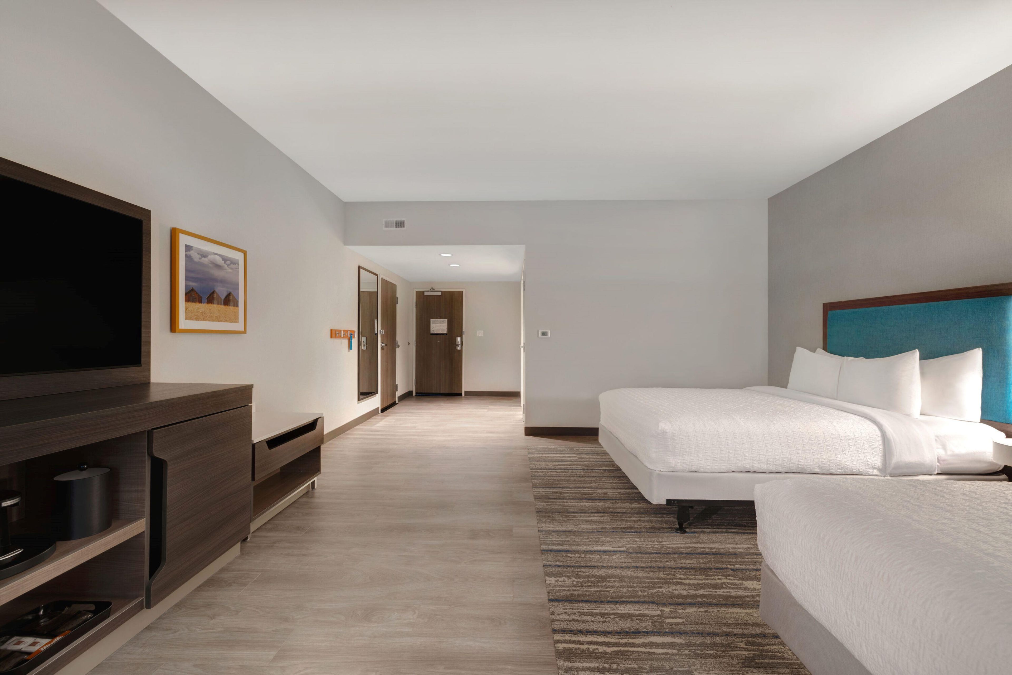 Une chambre d’hôtel avec un grand lit, une télévision, un bureau et un tableau encadré au mur.