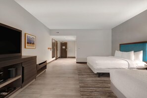 Une chambre d’hôtel avec un grand lit, une télévision, un bureau et un tableau encadré au mur.