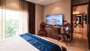 Quarto com uma cama grande, televisão na parede e cômoda.