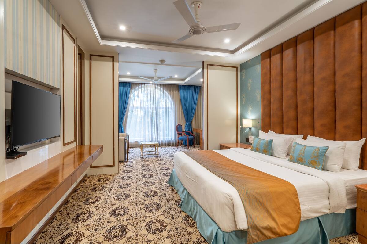 A hotel room with a bed, a TV, a desk, and a chair.