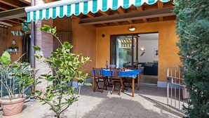 An outdoor patio with a table set for dining, surrounded by potted plants and a striped awning. - Regarda - "Costa del Sole" with swimming pool and terrace (Lazise)