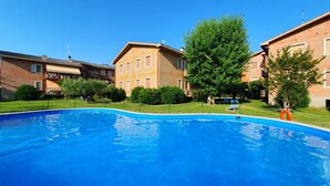 Ein Schwimmbecken, umgeben von Wohnhäusern, mit blauem Himmel.