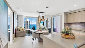 A modern kitchen with a dining area, large windows, and a view of the city. - Luxury Condo| Ocean View| Complementary Parking (Hollywood)