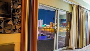 Ein modernes Hotelzimmer mit einer großen Schiebeglasdoor zu einem Balkon mit Blick auf die Stadt.