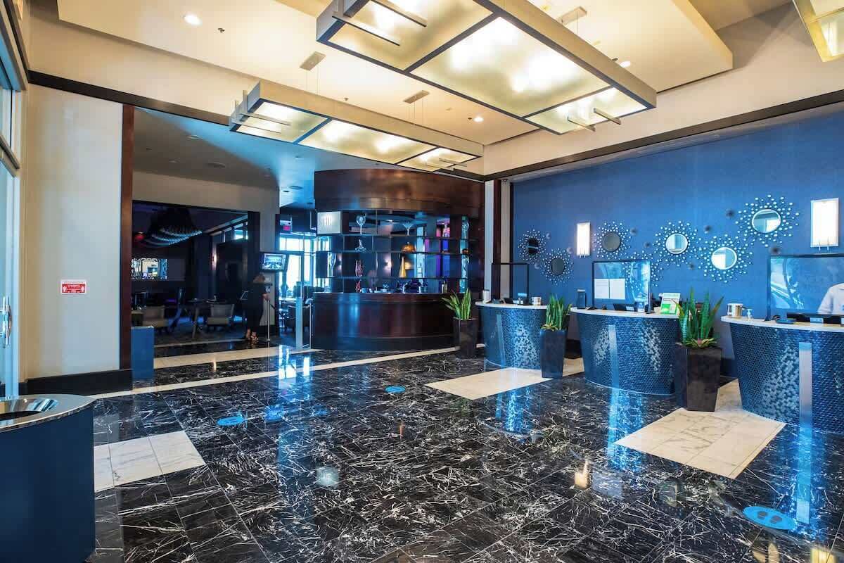 A modern hotel lobby with a marble floor, reception desks, and decorative wall art.