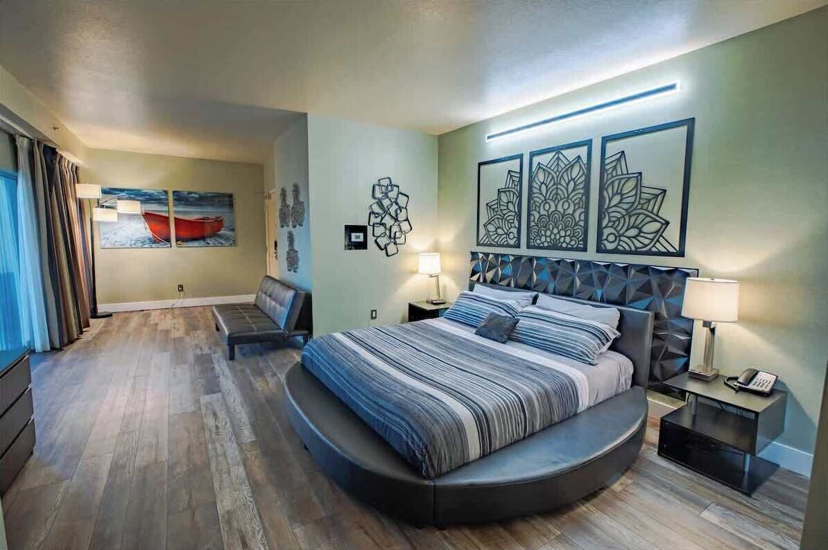 Ein modernes Schlafzimmer mit einem gewölbten Bett, einem Nachttisch mit Lampe und Bildern an den Wänden.