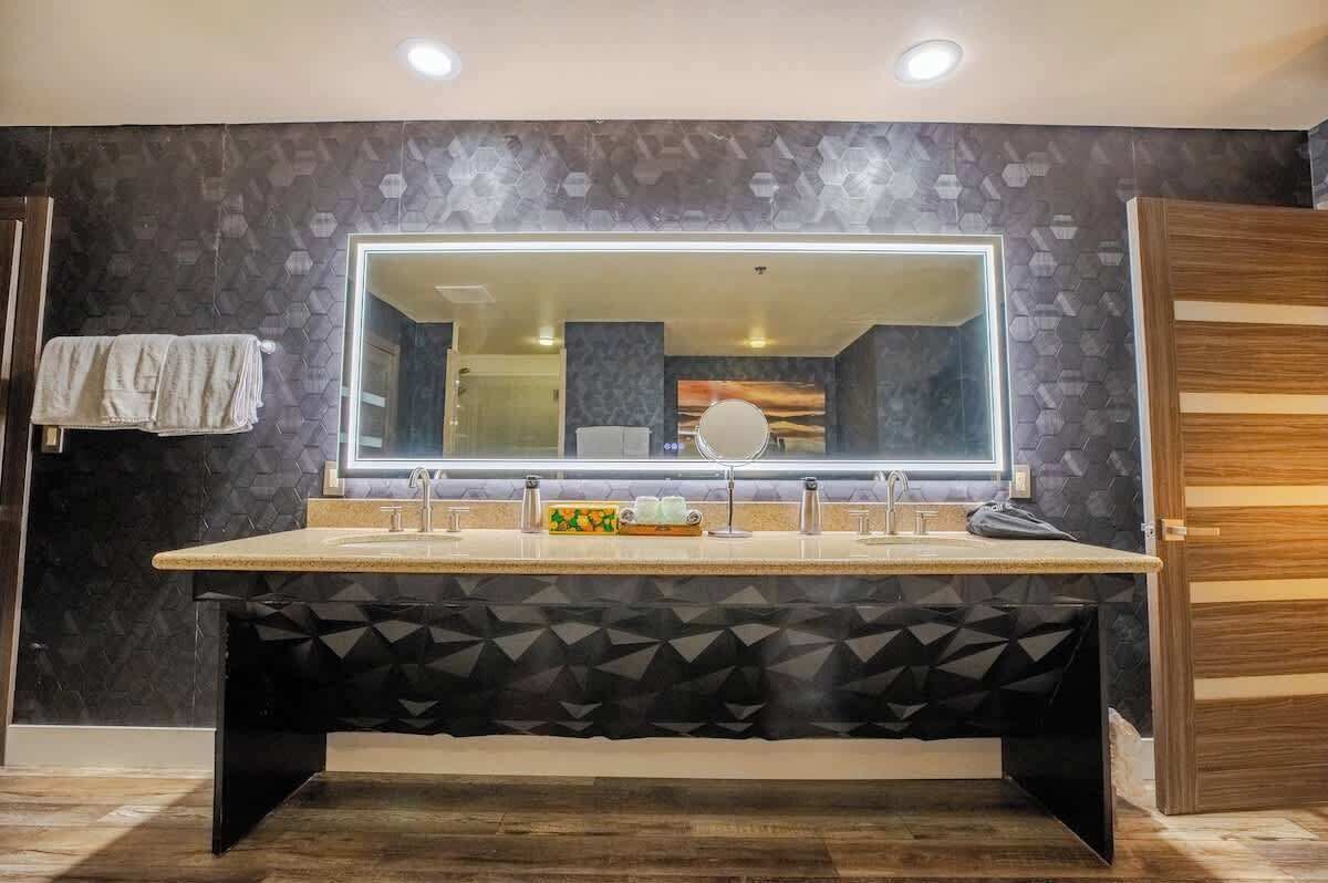 Un baño moderno con un espejo grande, dos lavamanos y un mueble de tocador.