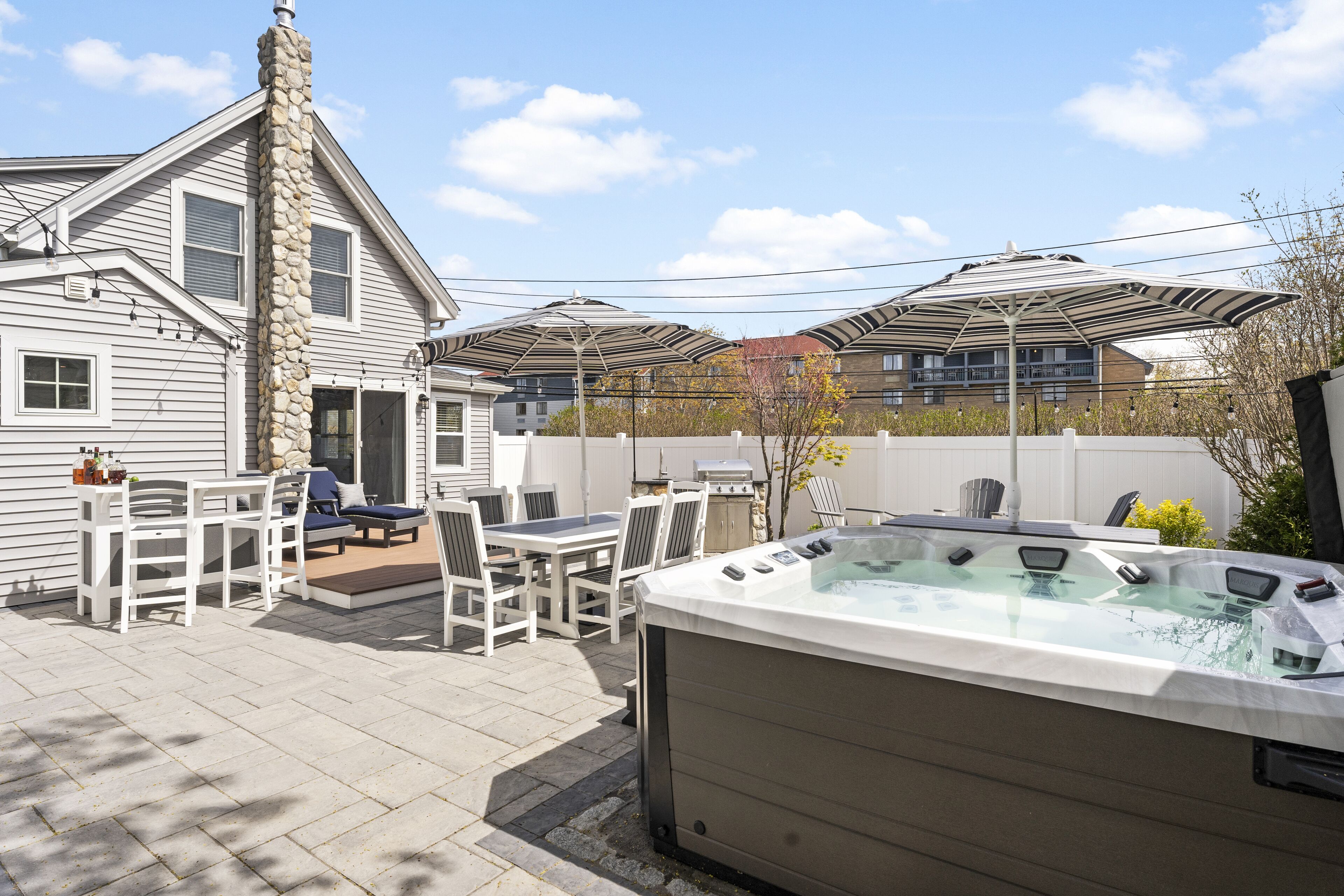 Un jardin avec un jacuzzi, un coin salon extérieur et une cheminée en pierre.