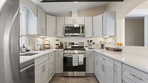 A modern kitchen with white cabinets, stainless steel appliances, and a central island. - Downtown Luxury Villa on the Plymouth Waterfront (Plymouth)
