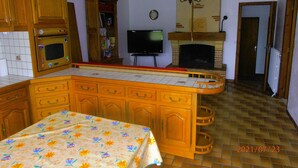 Una cocina con armarios de madera, un microondas, un televisor y una chimenea.