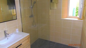 Un baño con ducha, lavamanos y ventana.