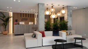 A modern hotel lobby with a reception desk, a sofa set, and pendant lighting.