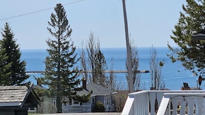 A residential area with a view of the ocean, a white staircase leading to a porch, and a small house with a stone foundation.