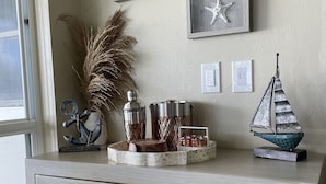 Een licht houten kast met een decoratief ingekerfd patroon, een scheepsmodel en een zeester decoratie aan de muur erboven.