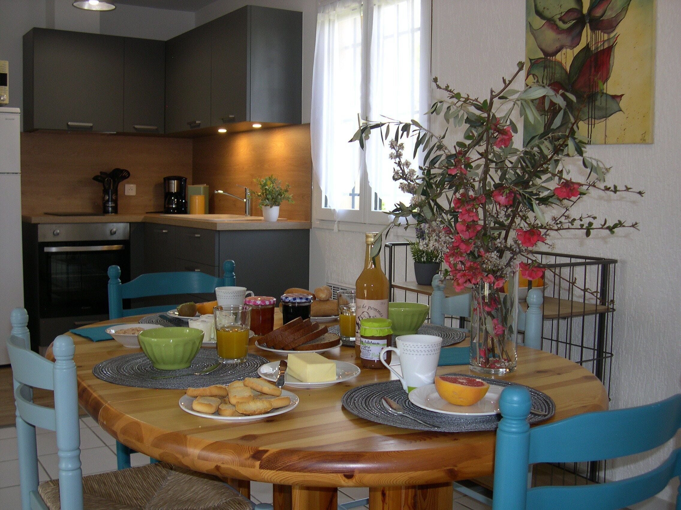 A dining area with a wooden table, blue chairs, and a vase with flowers.