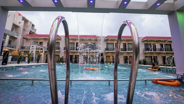 An indoor swimming pool with a view of a building with balconies and a red roof. - Moon Star Beach Resort (Kanthi)