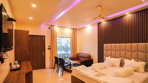 A hotel room with a bed, a desk, a chair, a table, and a balcony. - Moon Star Beach Resort (Kanthi)
