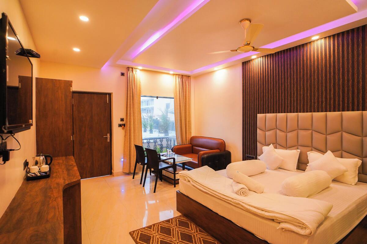 Ein Hotelzimmer mit Bett, Schreibtisch, Stuhl, Tisch und einem Balkon.