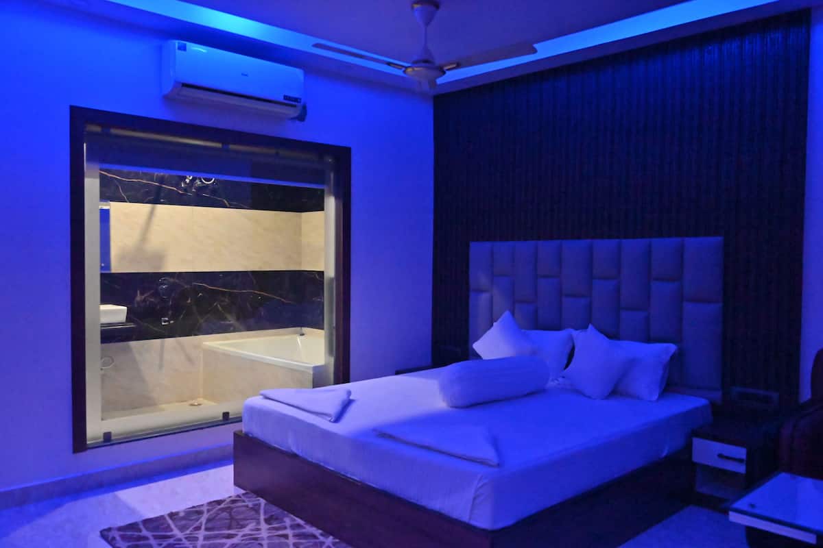 Ein modernes Schlafzimmer mit einem großen Bett, einer Glaskabine zur Badewanne und einem Deckenventilator.
