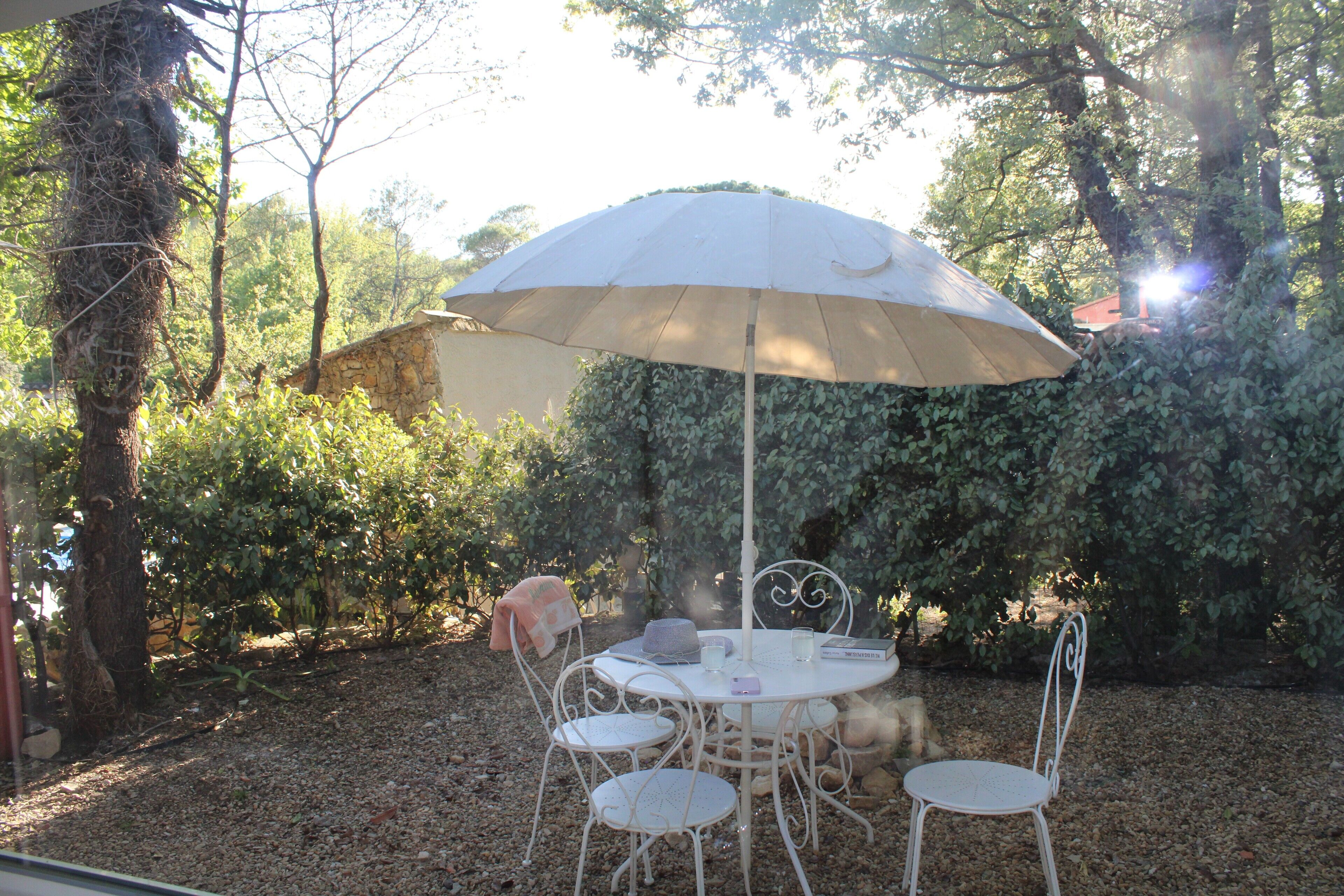 A round table with four chairs, an umbrella, and a box of tissues.
