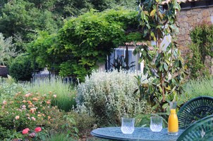 Un jardín con una mesa y sillas, rodeado de plantas y flores diversas.