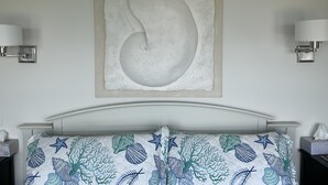 Une chambre à coucher comprenant un lit, une œuvre d’art accrochée au mur et deux appliques murales.