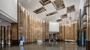 A spacious lobby with a high ceiling, modern lighting fixtures, and a large digital display. - Wyndham Garden Gaozhou (Maoming)