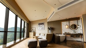 A modern bathroom with a large window, a bathtub, a vanity, and a sofa. - Wyndham Garden Gaozhou (Maoming)