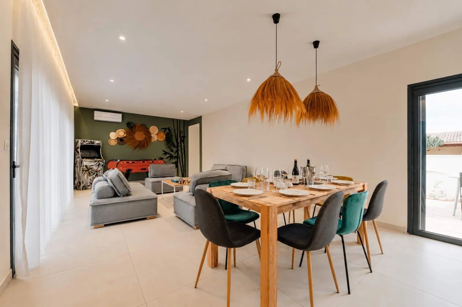 Uma sala de jantar moderna com uma mesa de madeira posta para quatro pessoas, cercada por cadeiras com estofamento preto e verde.