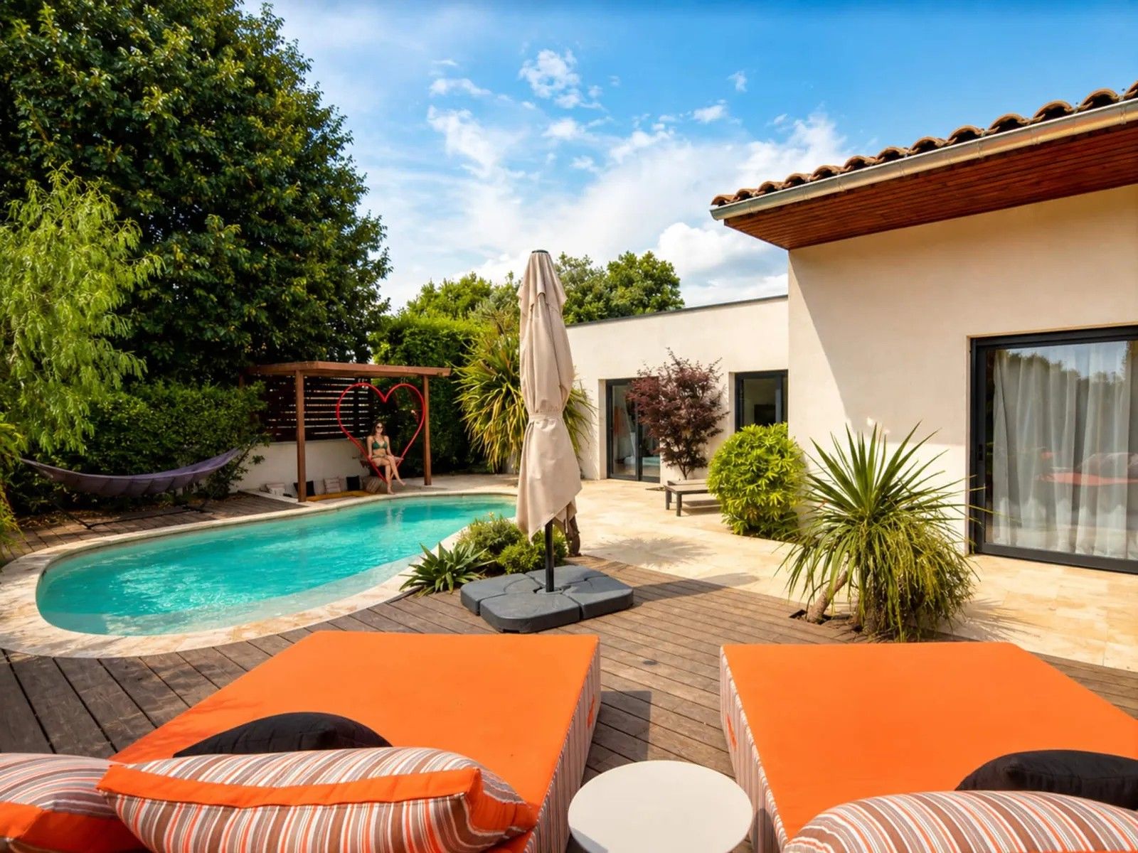 A swimming pool with a hammock, lounge chairs, and a pergola.