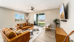 A spacious living room with a large sofa set, a coffee table, and a TV mounted on the wall. - Pueblo en Powell - Hot Tub, Game Room, Lake Views (Page)