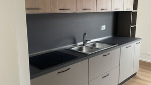 Een moderne keuken met grijze kastjes, een zwart aanrecht en een roestvrijstalen spoelbak.