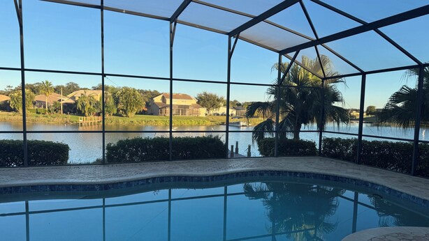A swimming pool with a view of a lake and houses in the background. - Magic Sunset (Kissimmee)