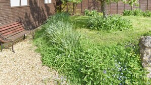 A wooden house with a bench and a garden with various plants and a tree. - 1 bedroom accommodation in Wellow, near Yarmouth (Wellow, near Yarmouth)