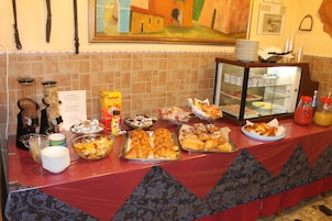 Una mesa de buffet con diversos alimentos, como pasteles, frutas y salsas.