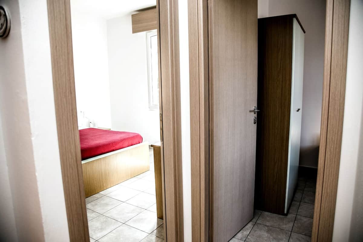 Un dormitorio con cama, una puerta de madera y suelo de baldosas.