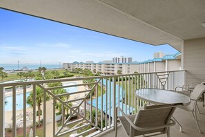 Un balcon avec vue sur une piscine, une plage et les bâtiments de l’hôtel.