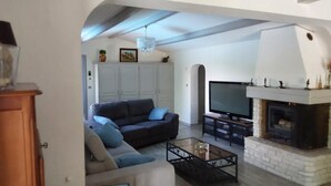 Ein Wohnzimmer mit Sofa, Couchtisch, Fernseher, Kamin und Schrank.
