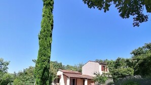 Ein ländliches Anwesen mit einem Schotterweg, der zu einem Haus mit roten Ziegeldach und einer Steinmauer führt.
