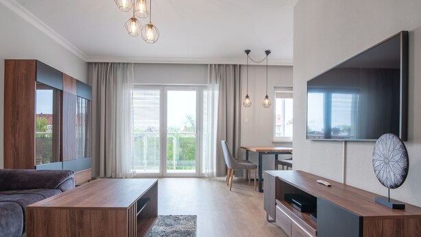 A modern living room with a sofa, coffee table, TV, and dining area.
