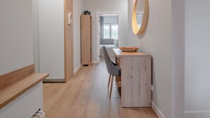 A hallway with a wooden bench, a desk with a bowl, and a mirror on the wall.