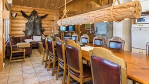 Interior de una cabaña de troncos con comedor, techo de madera y una gran escultura de piel.