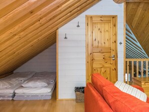 A loft bedroom with a wooden sloped ceiling, a single bed, a red sofa, and a wooden door. - Kaidan kunkku by Interhome (Ristiina)