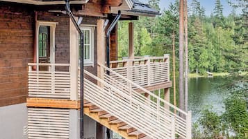 Una cabaña de madera con una escalera de madera que da a un balcón con vista a un lago.