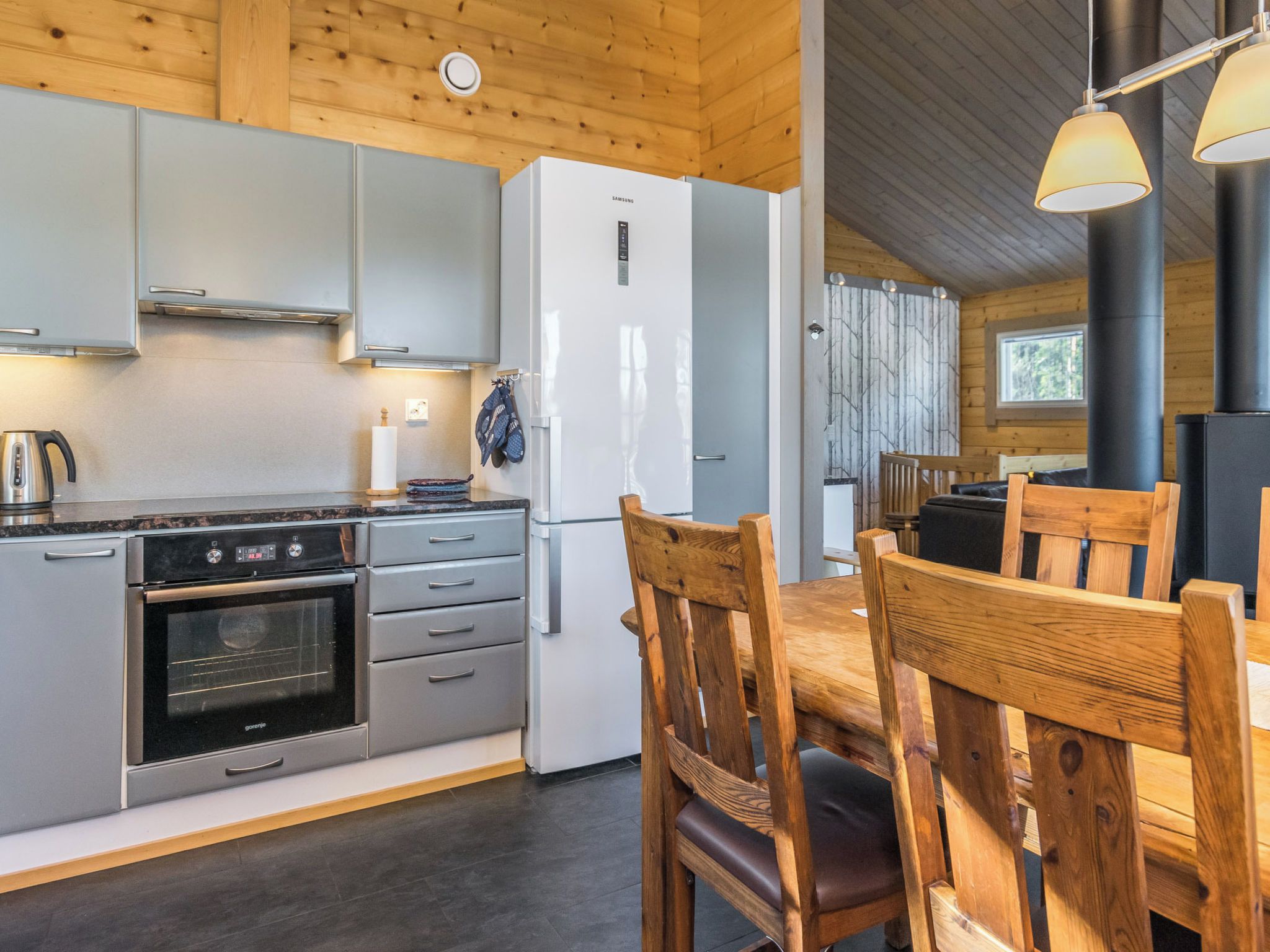 Eine moderne Küche mit Einbauofen, Kühlschrank und Essbereich mit Holzkästen.