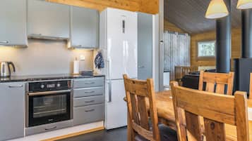 A modern kitchen with a built-in oven, a refrigerator, and a dining area with wooden chairs.