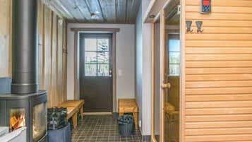 A room with a wood-burning stove, a bench, a door, and a window.